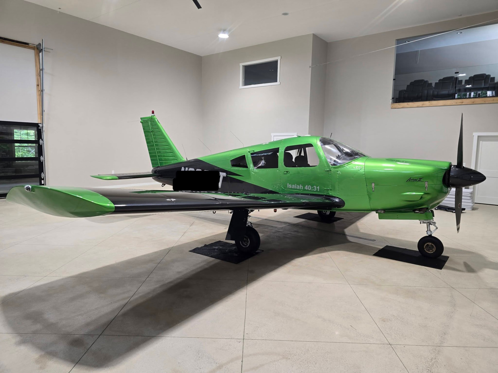 Green and black Piper Arrow airplane gleaming inside a hangar