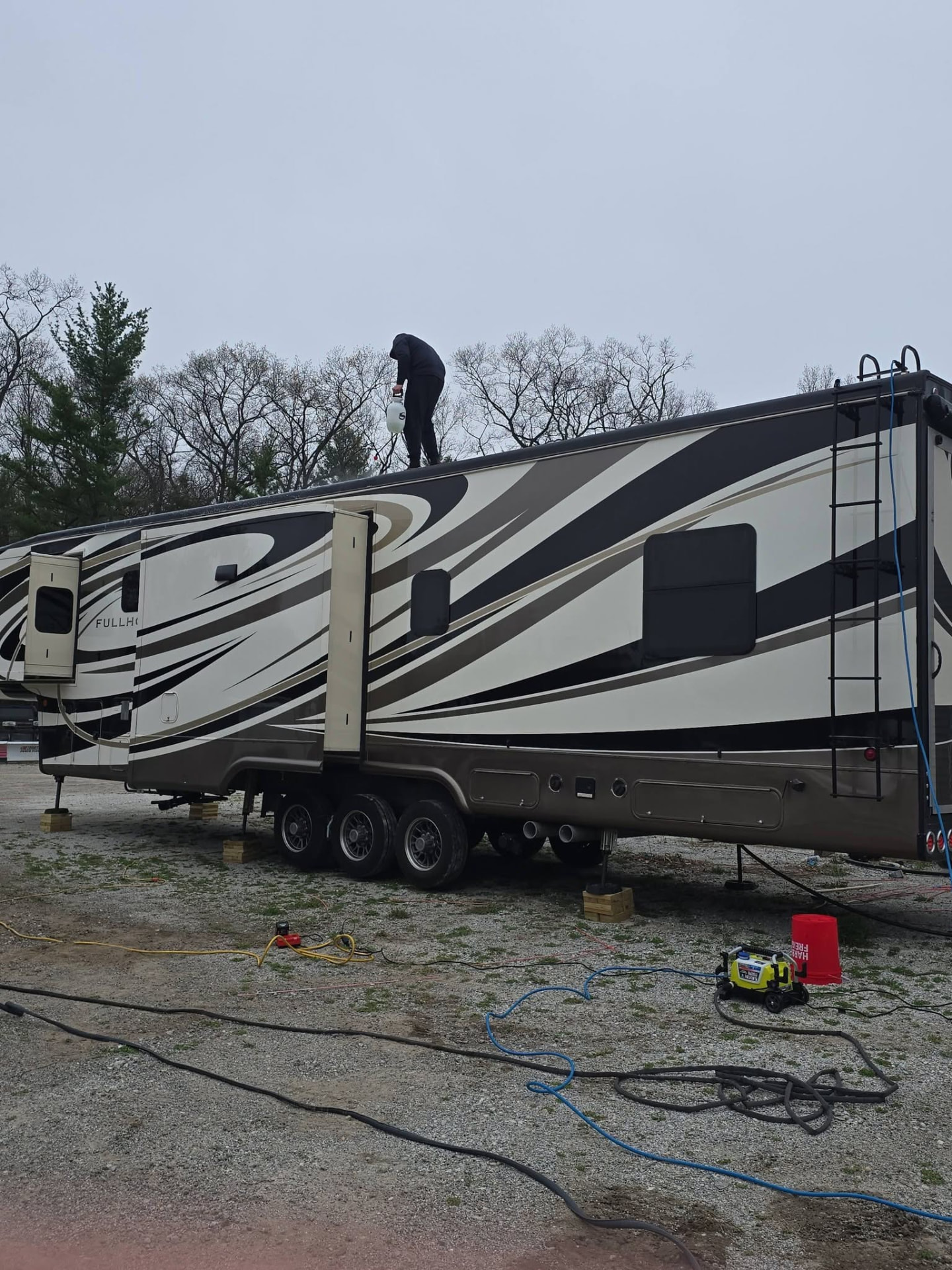 Detailer working on the roof of a large fifth-wheel RV